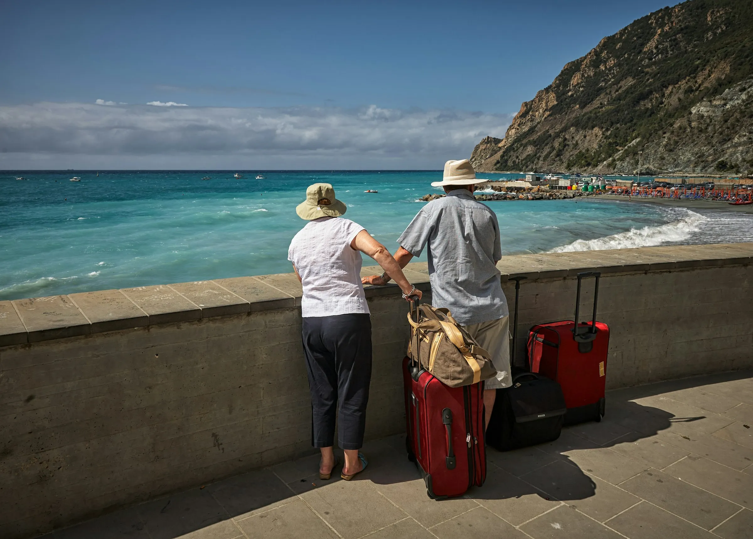 Two travellers with a suitcase looking out over the sea