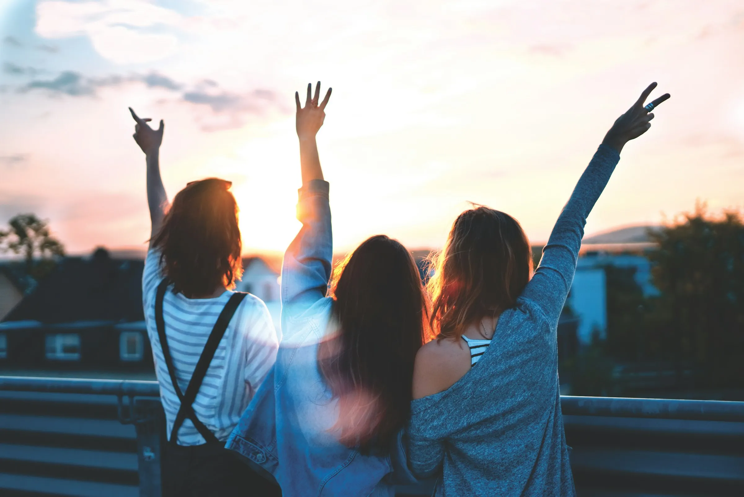 A group celebrating with arms raised at sunset