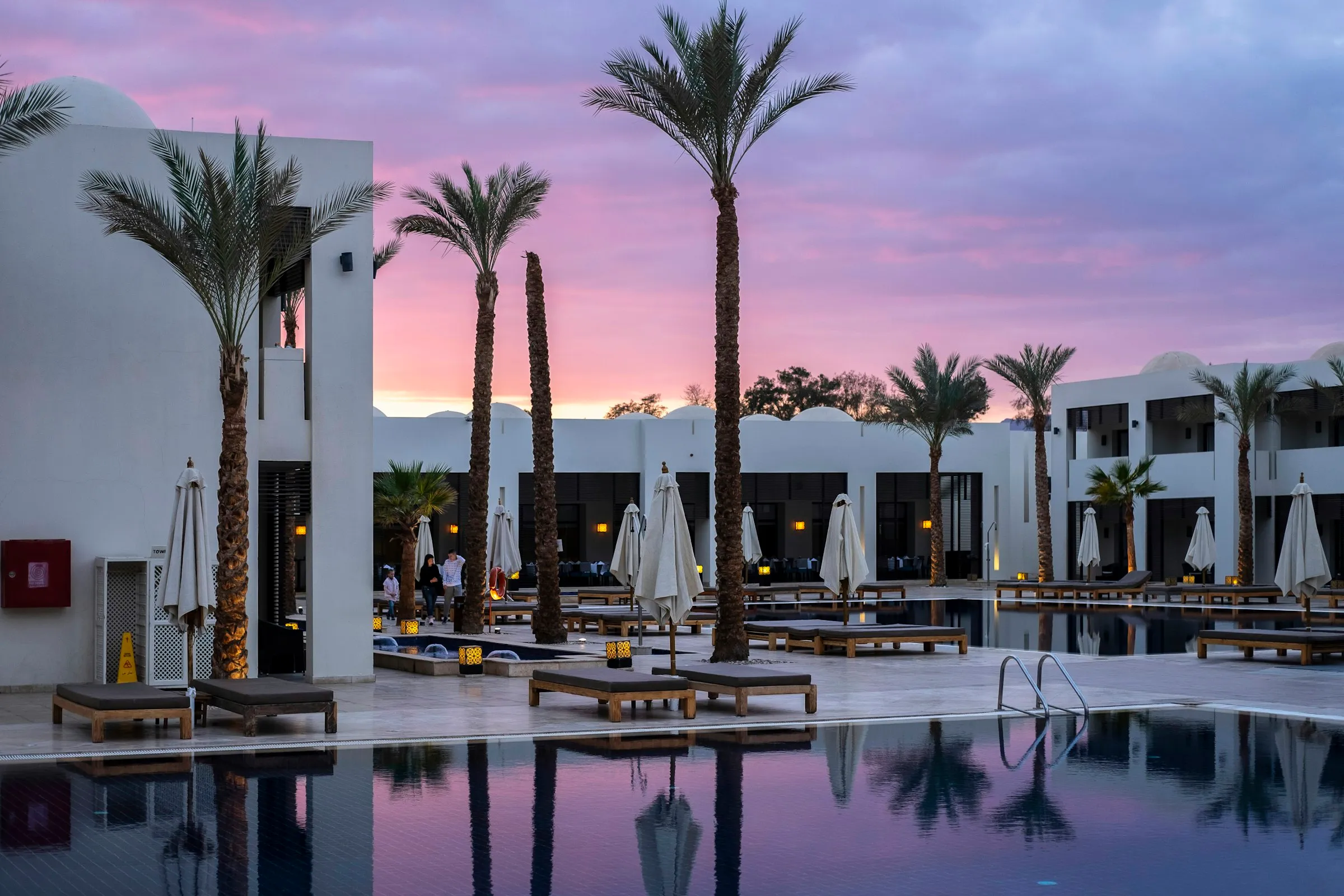 Palm trees and a hotel pool at sunset